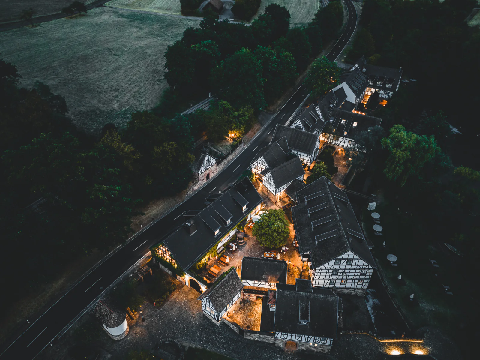 Das Anwesen des Neumühle Resort & SPA bei Nacht aus der Luft, mit warm beleuchtetem Innenhof.